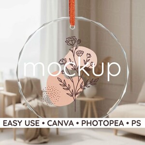 May include: A clear, round glass ornament with a floral design and the word "mockup" in white. The ornament has a red ribbon for hanging. The bottom of the image has the text "EASY USE • CANVA • PHOTOPEA • PS".