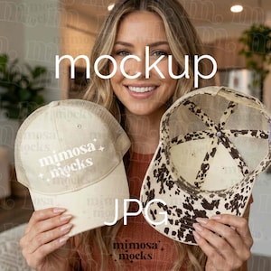 Puede incluir: Se muestran dos gorras de camionero. Una es de color crema con una parte trasera de malla y el texto "mimosa mocks". La otra gorra tiene un diseño de estampado de vaca. La palabra "mockup" se muestra en texto blanco.
