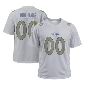 May include: A light gray V-neck sports jersey featuring the text YOUR TEAM on the front and YOUR NAME on the back, both with the number 00 in large gray digits with yellow outlines. The design includes small gray circular accents on the shoulders.