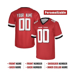 May include: A red sports jersey with white and black sleeve stripes, featuring the text YOUR NAME and the number 00 on the back, and YOUR TEAM and the number 00 on the front. The jersey includes a V-neck collar and is labelled as Personalizable.