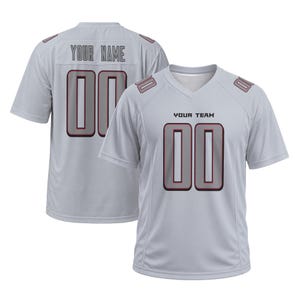 May include: A light gray short-sleeved sports jersey featuring a V-neck collar. The front displays the text YOUR TEAM above the number 00 in gray with black and red outlines. The back shows YOUR NAME above the number 00 with matching trim.