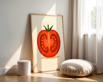 May include: A framed art print featuring a vibrant, cross-section illustration of a tomato. The artwork showcases the tomato's red flesh, seeds, and green stem against a cream-colored background. The print is leaning against a wall, near a white stool and a round floor cushion.