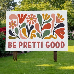 Könnte beinhalten: Ein weißes Schild mit einem farbenfrohen Blumendesign und dem Text "BE PRETTI GOOD" in Rot. Das Schild wird von zwei Holzpfosten getragen und steht in einem Rasen mit Bäumen und Blumen im Hintergrund.