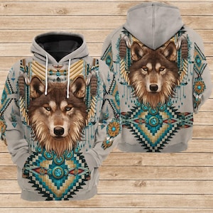 May include: A gray hoodie featuring a detailed wolf face design on the front and back. The design incorporates turquoise, gold, and brown geometric patterns and feather accents, creating a Native American-inspired aesthetic.