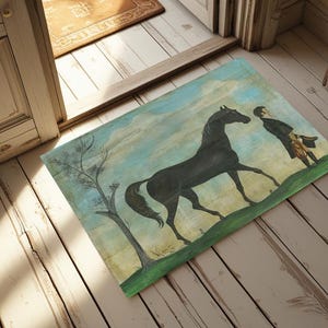 May include: Rectangular doormat depicting a black horse and a man in a field, set against a blue sky. A leafless tree is on the left. The mat is placed on a wooden floor.