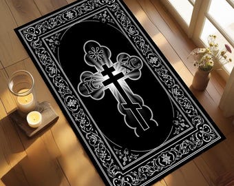 May include: Black rectangular rug with a white ornate border and a central design of a cross. The cross is black with white highlights and the letters IC XC. The rug is on a wooden floor, with candles and a vase of flowers visible.