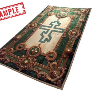 May include: Rectangular rug with a detailed design featuring a large teal cross in the center. The rug has a cream-colored background with a green border and ornate gold accents. The word "SAMPLE" is stamped in red in the upper left corner.