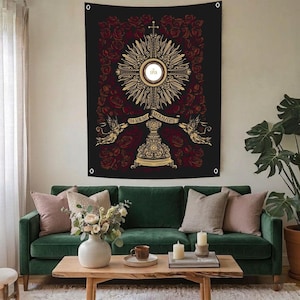 May include: Black tapestry with a gold and red religious design. The central image is a gold monstrance with a cross and the text "IHS". The design is surrounded by red roses and includes two angels. The tapestry is hanging above a green sofa.