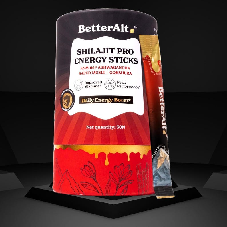 May include: A cylindrical container of BetterAlt Shilajit Pro Energy Sticks. The label features text including "Daily Energy Boost" and "Improved Stamina." A single stick is visible next to the container. The container is red and black with gold accents.