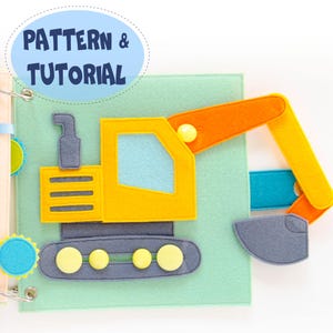 May include: A felt quiet book page with a yellow and orange excavator, blue window, and grey treads. The page is light green with the text "PATTERN & TUTORIAL" in a blue oval. The book is bound with metal rings.