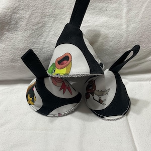 May include: Three black and white fabric pouches with cartoon character designs. Each pouch has a black loop handle. The pouches are stacked on top of each other, with the cartoon characters visible on the front.
