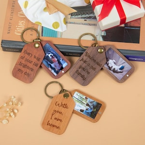 Könnte beinhalten: Holz-Schlüsselanhänger mit graviertem Text und Fotos von Haustieren. Einer lautet: "Every wag of your tail brightens my day." Ein anderer sagt: "You're not just a pet, you're family." Der letzte sagt: "With you, I am home."