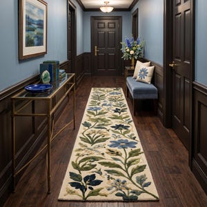 May include: A long rectangular area rug featuring a cream-colored background with a repeating pattern of blue and dark blue flowers, green leaves, and stems. The floral design runs the length of the rug, creating a botanical motif on the floor.