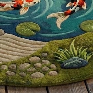 May include: A detailed rug depicting a koi pond scene. Two koi carp swim in blue water, with lily pads and a grassy bank. The rug has a textured, three-dimensional design with shades of green, beige, and brown.