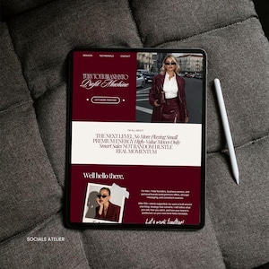 May include: A digital tablet displaying a website with a burgundy and white color scheme. The website's headline reads "Turn Your Brand Into Profit Machine." A white stylus rests beside the tablet on a gray fabric surface. The website features a photo of a woman.