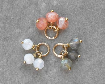 Pendiente de plata de ley con abalorio de piedra en forma de trío pequeño: piedra lunar blanca, piedra solar naranja y labradorita gris.