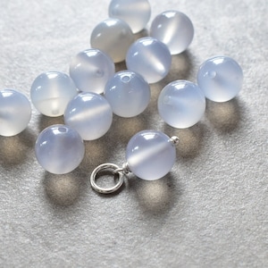 May include: A collection of light blue agate beads, some of which are strung on a silver chain.