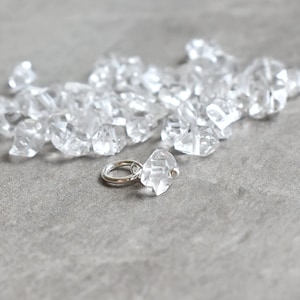 May include: A pile of clear quartz crystals with a silver jump ring.