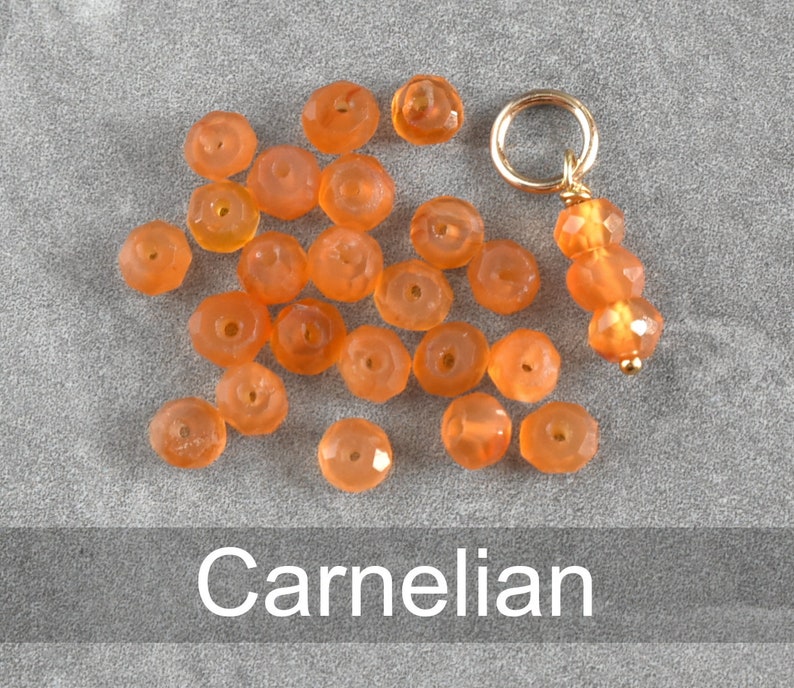 K&ouml;nnte beinhalten: Eine Sammlung von Karneolperlen in verschiedenen Oranget&ouml;nen, mit einem goldenen Anh&auml;nger an einer Schnur. Die Perlen sind facettiert und haben eine polierte Oberfl&auml;che.