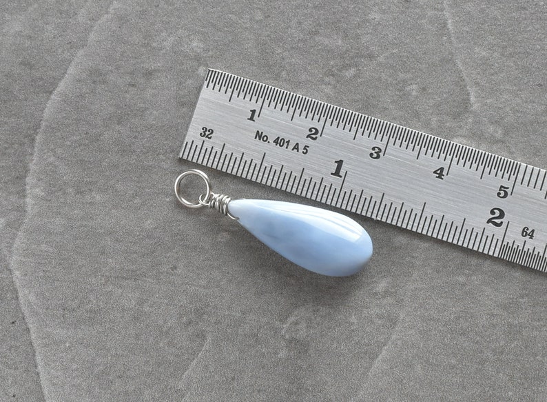 May include: A light blue teardrop-shaped pendant made of opal, approximately 1 inch long, with a silver wire wrap and a silver jump ring.
