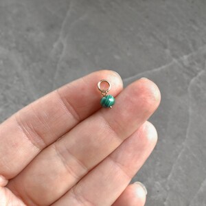 May include: A small green malachite bead charm with a gold jump ring.
