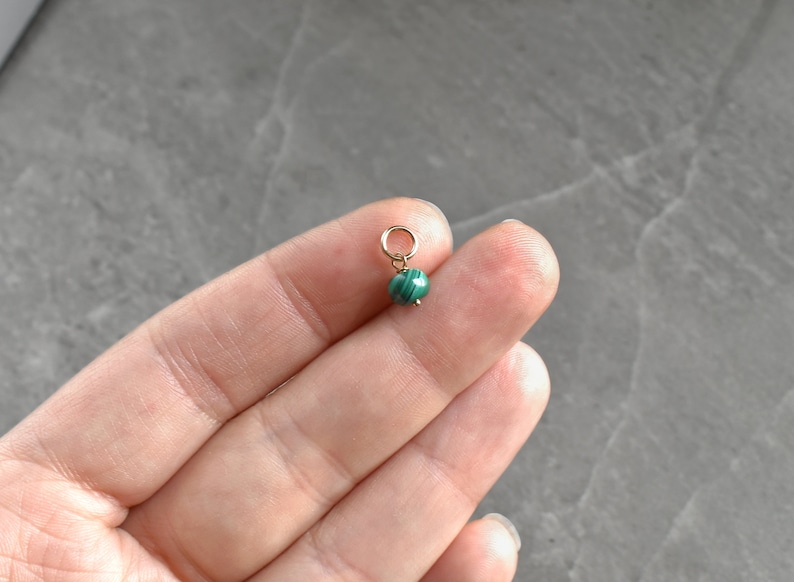 May include: A small green malachite bead charm with a gold jump ring.