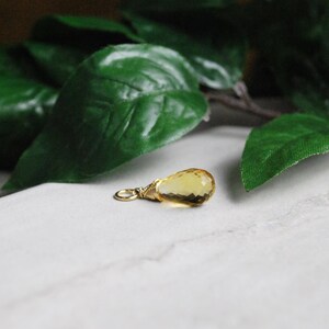 Puede incluir: Un peque&ntilde;o colgante de piedra preciosa amarilla en forma de l&aacute;grima con un envoltorio de alambre dorado.