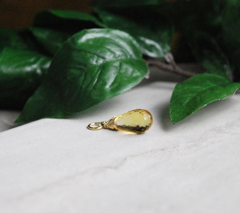 Puede incluir: Un peque&ntilde;o colgante de piedra preciosa amarilla en forma de l&aacute;grima con un envoltorio de alambre dorado.
