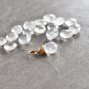 Puede incluir: Una colecci&oacute;n de cuentas de piedra lunar blanca con un colgante de piedra lunar envuelto en alambre dorado.