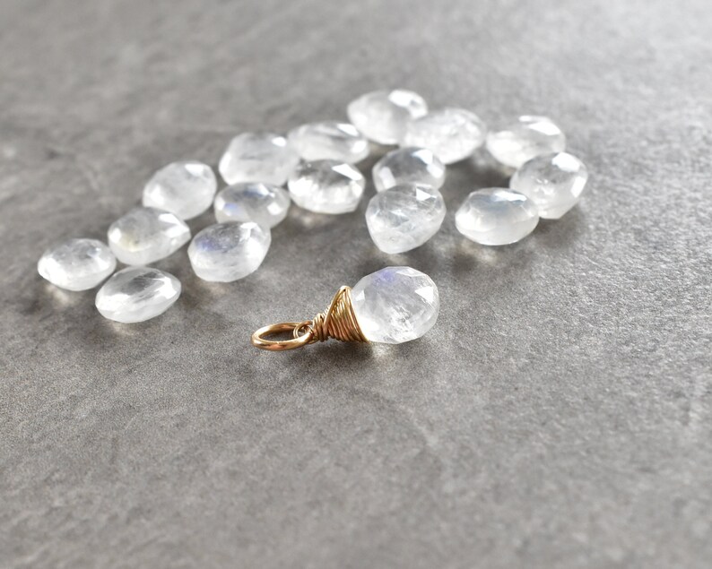 Puede incluir: Una colecci&oacute;n de cuentas de piedra lunar blanca con un colgante de piedra lunar envuelto en alambre dorado.