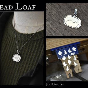 May include: A silver pendant necklace featuring a sleeping cat design. The pendant is rectangular with rounded edges and a silver chain. The image also shows a close-up of the pendant and a workbench with cat-shaped cutouts.