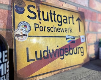 Letrero de calle vintage de Stuttgart: Arte mural de garaje con una cueva de hombre oxidada
