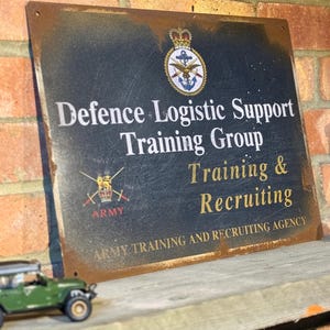May include: A rectangular, distressed metal sign with the text "Defence Logistic Support Training Group Training & Recruiting." The sign features the Army logo and the text "Army Training and Recruiting Agency."