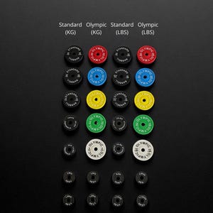 K&ouml;nnte beinhalten: Eine Sammlung von Hantelscheiben in verschiedenen Farben und Gr&ouml;&szlig;en, angeordnet auf einer schwarzen Oberfl&auml;che. Die Scheiben sind mit Gewichtsangaben in Kilogramm (KG) und Pfund (LBS) beschriftet. Die W&ouml;rter "Standard" und "Olympic" sind ebenfalls sichtbar.