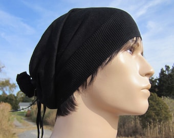 May include: A black knit beanie with a long tie that can be tied at the back of the neck. The beanie is made of a soft, stretchy material.