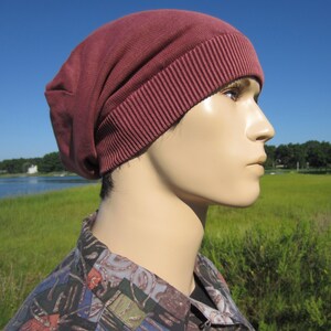 May include: A maroon beanie with a ribbed brim. The beanie is made of a soft, stretchy fabric.