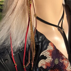 May include: A red, brown, and gold hair chain with beads and tassels. The chain is hanging from a mannequin's hair.