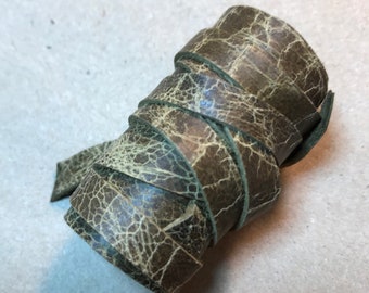 May include: A roll of dark green leather cord with a cracked and textured surface.