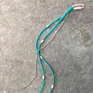 May include: A turquoise blue hair clip with a silver chain and beads. The clip is made of metal and has a simple design.