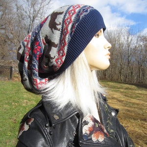 May include: A woman wearing a blue and grey knitted beanie with a geometric pattern and a black leather jacket with floral embroidery.