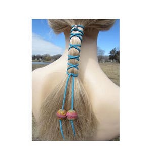 Peut inclure: Un enrouleur de cheveux en cuir turquoise avec des perles colorées nouées autour d'une queue de cheval.