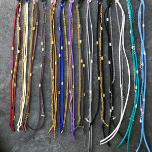 May include: Assortment of 14 hair clips with multiple strands of chain and suede in various colors, including red, white, brown, gold, blue, purple, gray, black, turquoise, and light blue.