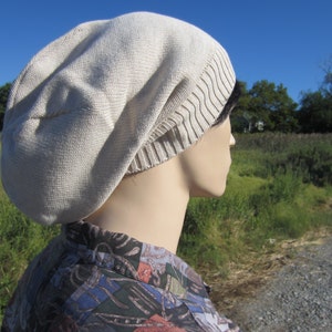 May include: A beige slouchy beanie with a ribbed brim. The beanie is made of a soft, knitted fabric.