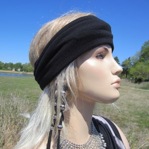 May include: A black headband with a silver beaded hair tie. The headband is worn by a person with long, blonde hair. The person is looking off to the side.