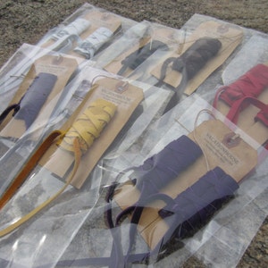 May include: Assortment of leather shoe laces in various colors, including yellow, red, purple, and blue, packaged in clear plastic bags with brown paper tags that read "Vacationhouse".