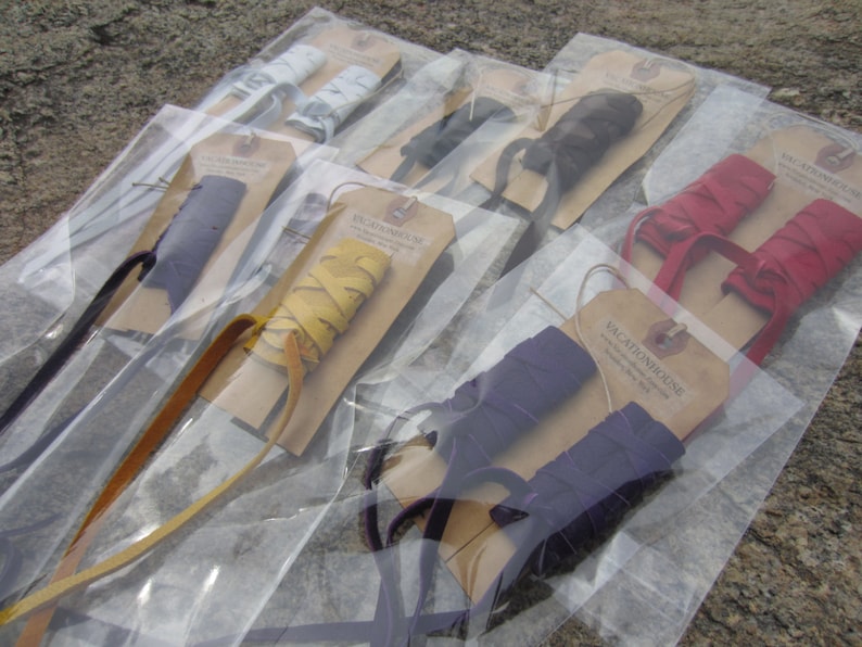 May include: Assortment of leather shoe laces in various colors, including yellow, red, purple, and blue, packaged in clear plastic bags with brown paper tags that read "Vacationhouse".