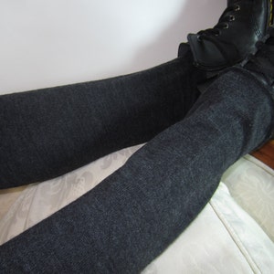 K&ouml;nnte beinhalten: Dunkelgraue Leggings kombiniert mit schwarzen Lederstiefeln. Die Leggings sind einfarbig und scheinen aus einem weichen Strickstoff zu bestehen. Die Stiefel haben Schn&uuml;rsenkel und ein klassisches Design.