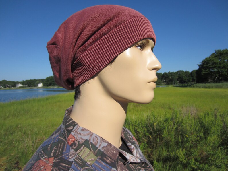 May include: A maroon beanie with a ribbed brim. The beanie is made of a soft, stretchy fabric.