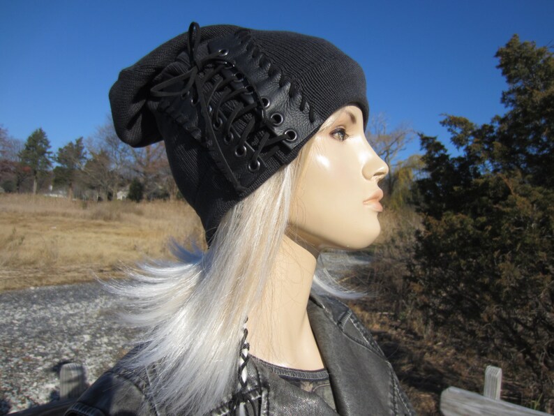 May include: A black beanie with a leather lace detail. The beanie is made of a soft, knit fabric and has a slouchy fit.