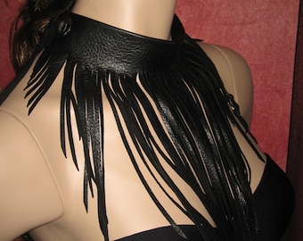 Puede incluir: Un collar gargantilla de cuero negro con flecos largos. Los flecos cuelgan en la parte delantera del cuello y el pecho.
